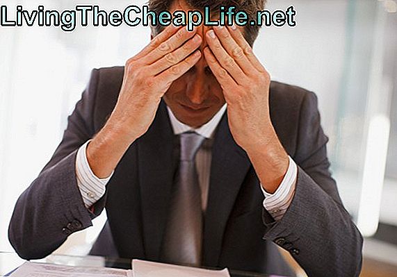 Frustrerad affärsman sitter vid skrivbordet med huvud i händerna