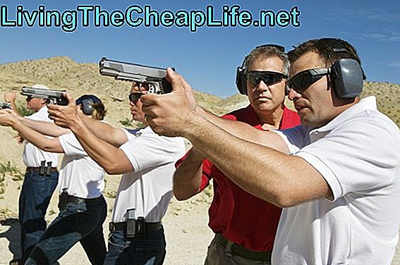 Istruttore che assiste gli uomini che mirano le pistole della mano al poligono di tiro