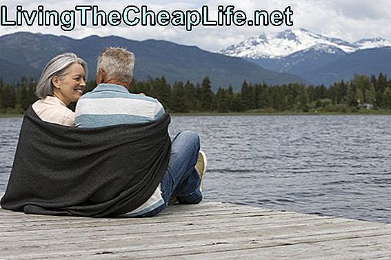 Äldre par sitter på bryggan insvept med blanked, bergskedja i bakgrunden